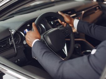 Man buying the car. Businessman in a car salon. Black male in a suit.